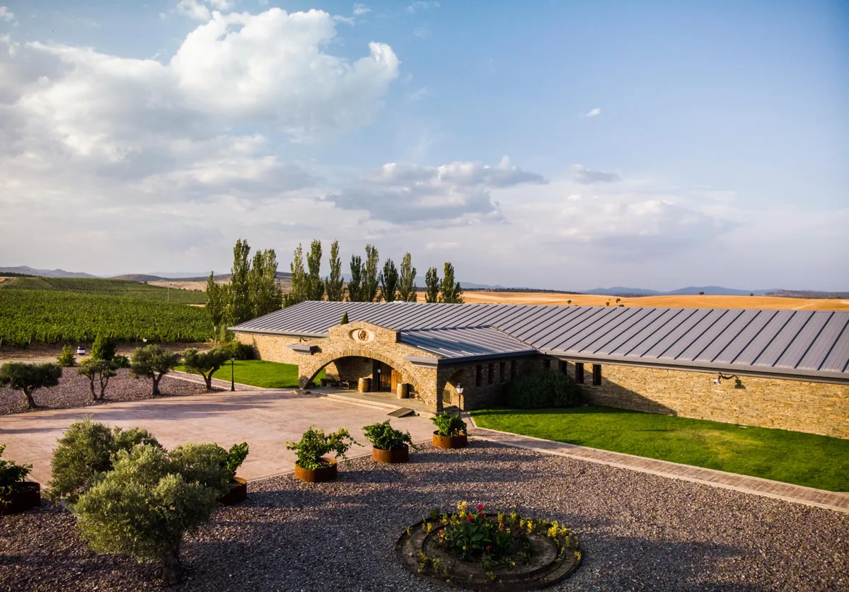 Patio y edificios de piedra de la bodega Finca Río Negro, rodeados de viñedos